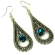 Boucles d'oreilles pendantes en metal argente cisele serties de pierres bleu clair