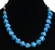 Collier ethnique artisanal imitation boules turquoises difformes separees de perles en metal et compose d'autres perles noires et blanches